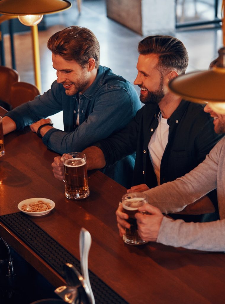 top-view-of-bartender-serving-beer-to-young-men-while-standing-at-the-bar-counter-in-pub.jpg